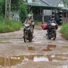"Ổ gà", "ổ voi" chằng chịt, dày đặc trên mặt đường bị mất lớp nhựa của tuyến đường DH85, gây khó khăn cho các phương tiện giao thông. (Ảnh: Dư Toán/TTXVN)
