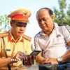 Cán bộ Cảnh sát giao thông Tây Ninh tuyên truyền pháp luật đến các chủ phương tiện. (Ảnh: Giang Phương/TTXVN)