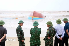 Lên phương án trục vớt tàu cá bị đánh chìm và dạt vào tại khu vực biển xã Bắc Trạch. (Ảnh: Tá Chuyên/TTXVN)
