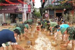 Cán bộ, chiến sỹ lực lượng chức năng hỗ trợ người dân khắc phục thiên tai. (Ảnh: TTXVN phát)
