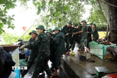 Các chiến sỹ Bộ Chỉ huy Quân sự tỉnh Tuyên Quang hỗ trợ người dân nhà bè trên sông Lô gia cố nơi ở. (Ảnh: Quang Cường/TTXVN)