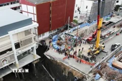 Một đoạn đường trước bệnh viện Vajira đã bất ngờ bị sụt, tạo thành hố lớn có diện tích 30x30m và sâu tới 50m. (Ảnh: Reuters/TTXVN)