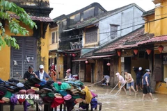 Người dân dọn bùn tại ngã tư Nguyễn Thái Học-Lê Lợi, phường Hội An. (Ảnh: Kha Phạm/TTXVN)