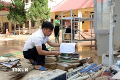 Thầy Hoàng Hữu Dương, Hiệu trưởng Trường Trung học cơ sở xã Yên Bình, tỉnh Lạng Sơn đang xem lại những tài liệu, đồ dùng dạy học nào còn dùng được sẽ cố gắng tận dụng. (Ảnh: Văn Đạt/TTXVN)