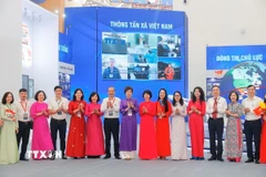 Tổng Giám đốc Vũ Việt Trang cùng các đại biểu tại gian trưng bày của TTXVN. (Ảnh: Minh Quyết/TTXVN)