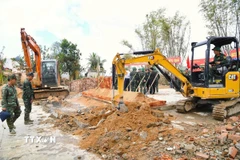 Lực lượng quân đội cùng nhiều phương tiện, máy móc được huy động hỗ trợ người dân xây nhà mới. (Ảnh: Tường Quân/TTXVN)