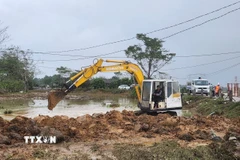 Xe múc được huy động khắc phục đoạn đê bị sạt lở do mưa lũ kéo dài. (Ảnh: Mai Trang/TTXVN)