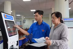 Thanh niên tình nguyện phường Rạch Giá, An Giang, hướng dẫn người dân đăng ký giải quyết thủ tục hành chính trên hệ thống. (Ảnh: Văn Sĩ/TTXVN)