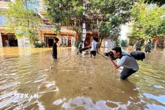 Phóng viên Nguyễn Quang Cường, CQTT tại tỉnh Tuyên Quang, tác nghiệp tại phường Minh Xuân, thời điểm cơn bão số 10 gây ảnh hưởng. (Ảnh: TTXVN)