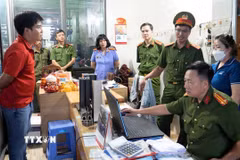 Lực lượng chức năng khám xét nơi làm việc của các bị can. (Ảnh: TTXVN phát)
