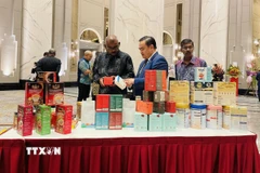 Tham tán Thương mại Việt Nam tại Malaysia Lê Phú Cường (giữa) giới thiệu với khách mời các sản phẩm truyền thống của Việt Nam. (Ảnh: Thành Trung/TTXVN)