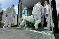 Các nhân viên chuyển thi thể binh sỹ Ukraine từ xe vận chuyển đông lạnh để hồi hương gần Novaya Guta, Belarus vào ngày 19/8. (Nguồn: AP)