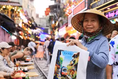 Một người hàng rong bán tranh in "phố càphê đường tàu." (Ảnh: Thành Phương/TTXVN)