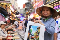 Một người hàng rong bán tranh in "phố càphê đường tàu." (Ảnh: Thành Phương/TTXVN)