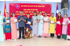 Đại diện Đại sứ quán Việt Nam tại Lào và Hội người Việt Nam thủ đô Vientiane trao quà cho các thầy cô giáo. (Ảnh: Bá Thành/TTXVN)