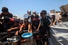 Người dân Palestine chờ nhận thức ăn cứu trợ tại thành phố Gaza. (Ảnh: THX/TTXVN)