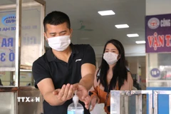 Hành khách sát khuẩn tay trước khi vào bến xe Giáp Bát. (Ảnh: Hoàng Hiếu/TTXVN)