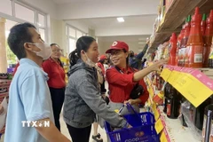 Nhân viên Hội Chữ thập Đỏ Đà Nẵng hỗ trợ người dân lựa chọn các nhu yếu phẩm tại Chương trình Tết Nhân ái. (Ảnh: Trần Lê Lâm/TTXVN)