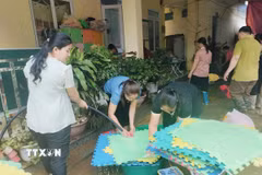 Giáo viên Trường Mầm non và Tiểu học Minh Long khẩn trương khắc phục hậu quả mưa lũ. (Ảnh: TTXVN phát)