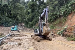 Lực lượng chức năng xử lý một điểm sạt lở trên Tỉnh lộ 673. (Ảnh: Cao Nguyên/TTXVN)