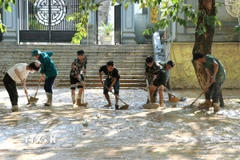 Người dân dọn bùn đất trên các tuyến đường ở phường Hà Giang 1 (Tuyên Quang). (Ảnh: Đức Thọ/TTXVN)