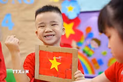 Trẻ thật vui và tự hào khi hoàn thành sản phẩm là lá cờ Tổ quốc của mình. (Ảnh: Thanh Tùng/TTXVN)