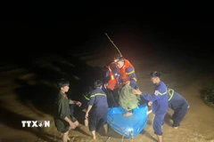 Các lực lượng chức năng cứu hộ thành công 6 người dân bị cô lập vì nước lũ đến nơi an toàn trong đêm. (Ảnh: TTXVN phát)