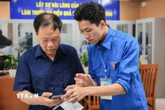 Đoàn viên thanh niên hướng dẫn người dân sử dụng, khai báo, các dịch vụ công trực tuyến trên điện thoại thông minh. (Ảnh: Hoàng Hiếu/TTXVN)