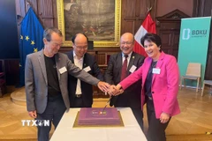 Giám đốc HUST Huỳnh Quyết Thắng và Hiệu trưởng BOKU Eva Schulev-Steindl thực hiện nghi thức kỷ niệm quan hệ hợp tác 25 năm giữa hai trường đại học. (Ảnh: TTXVN phát)