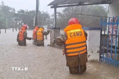 Lực lượng Công an hỗ trợ di dời người dân vùng ngập sâu đến nơi an toàn. (Ảnh: TTXVN phát)