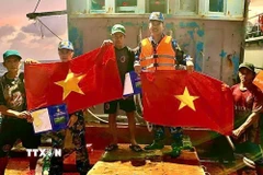 Cán bộ, chiến sỹ Vùng 2 Hải quân tuyên truyền, tặng cờ cho ngư dân trên biển. (Ảnh: TTXVN phát)