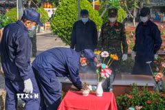 Lực lượng chuyên môn tiến hành đưa hài cốt liệt sỹ ra khỏi mộ để lấy mẫu giám định. (Ảnh: Thanh Liêm/TTXVN)