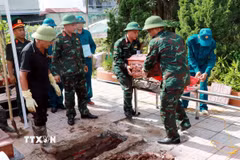 Hài cốt liệt sỹ được hoàn táng đúng vị trí ban đầu trong các phần mộ tại nghĩa trang sau khi lấy mẫu sinh phẩm. (Ảnh: Nguyễn Lành/TTXVN)