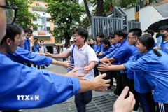 Các bạn sinh viên tình nguyện chia sẻ niềm vui và khích lệ tinh thần thí sinh tại điểm trường THCS Ngô Sĩ Liên (quận Hai Bà Trưng). (Ảnh: Khánh Hòa/TTXVN_