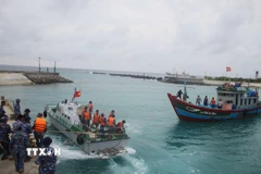 Xuồng cứu hộ của đảo Song Tử Tây (bên trái) đang lai kéo tàu cá QNg 96318-TS vào âu tàu. (Ảnh: TTXVN phát)