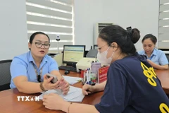 Công chức phường Mạo Khê, Quảng Ninh, hướng dẫn công dân nộp hồ sơ chứng thực lên Cổng dịch vụ công Quốc gia. (Ảnh: Thanh Vân/TTXVN)