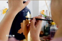 Vẽ hoa văn trên sản phẩm gốm sứ tại làng nghề Hạ Thái. (Ảnh: Trần Việt/TTXVN)
