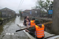 Bộ đội Biên phòng Hà Tĩnh hỗ trợ di dời người dân ra khỏi vùng ngập lụt. (Ảnh: Hoàng Ngà/TTXVN)