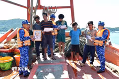 Bộ Tư lệnh Vùng Cảnh sát biển 4 tuyên truyền chống khai thác IUU và tặng cờ Tổ quốc, ảnh Bác Hồ, túi thuốc y tế cho các tàu cá đang hoạt động trên biển. (Ảnh: Văn Sĩ/TTXVN)