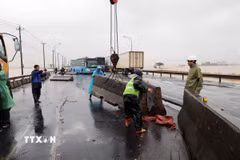 Nỗ lực khắc phục dải phân cách cứng bị trôi dạt trên Quốc lộ 1A. (Ảnh: Đỗ Trưởng/TTXVN)