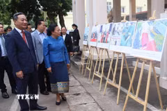 Đại sứ Nguyễn Minh Tâm và các đại biểu Lào nghe giới thiệu về những dấu ấn trong quan hệ gắn kết chiến lược Việt Nam-Lào. (Ảnh: Xuân Tú/TTXVN)