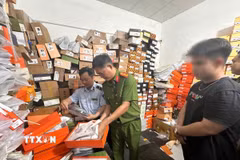 Công an thành phố Cần Thơ phối hợp Chi Cục quản lý thị trường thành phố kiểm đếm số quần áo “giả” thương hiệu nổi tiếng tại cửa hàng T.H Luxury. (Ảnh: TTXVN phát)