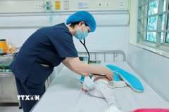 Bác sỹ khám cho bệnh nhi mắc ho gà đang điều trị tại Trung tâm bệnh Nhiệt đới (Bệnh viện Nhi Trung ương). (Ảnh: Minh Quyết/TTXVN)