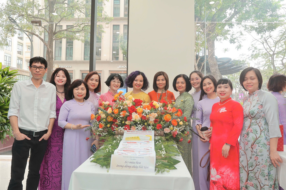 Cán bộ nữ Trung tâm Thông tin Tư liệu và Đồ họa "tươi không cần tưới" bên hoa. (Ảnh: Vietnam+)