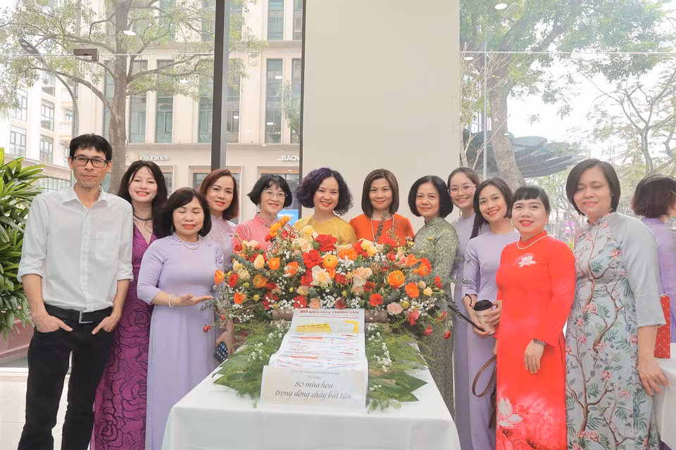 Cán bộ nữ Trung tâm Thông tin Tư liệu và Đồ họa "tươi không cần tưới" bên hoa. (Ảnh: Vietnam+)