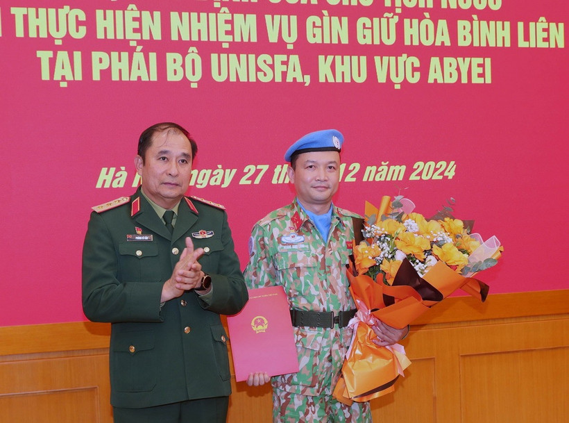 Thượng tướng Phùng Sĩ Tấn, Phó Tổng Tham mưu trưởng Quân đội Nhân dân Việt Nam trao quyết định và tặng hoa cho Thiếu tá Hoàng Đình Công trước khi lên đường. (Ảnh: Trọng Đức/TTXVN)