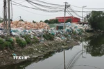 Rác thải nhựa của thôn Minh Khai được tập kết ngay cạnh bờ sông, gây ô nhiễm nghiêm trọng môi trường nguồn nước. (Ảnh: Mạnh Khánh/TTXVN)