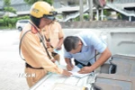 Cảnh sát giao thông lập biên bản một trường hợp tài xế xe khách vi phạm. (Ảnh: Linh Sơn/TTXVN)