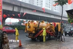 Công nhân ứng trực tiêu thoát nước trong mưa lớn tại đường Nguyễn Xiển. (Ảnh: Nguyễn Thắng/TTXVN)
