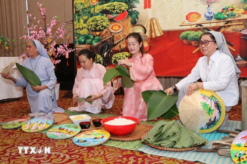 Các sơ cùng đại diện cộng đồng mô phỏng nét đẹp gói bánh chưng tại buổi lễ. (Ảnh: TTXVN phát)